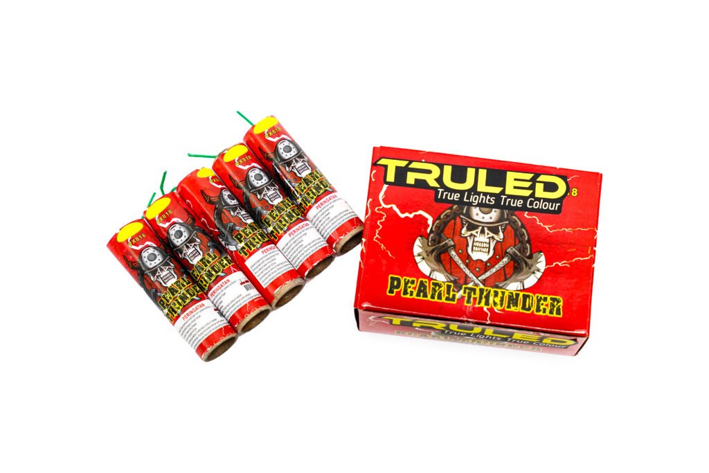 Row of red firework tubes with yellow tips arranged next to a red box labeled 'TRUELED' with skull-and-lightning artwork.