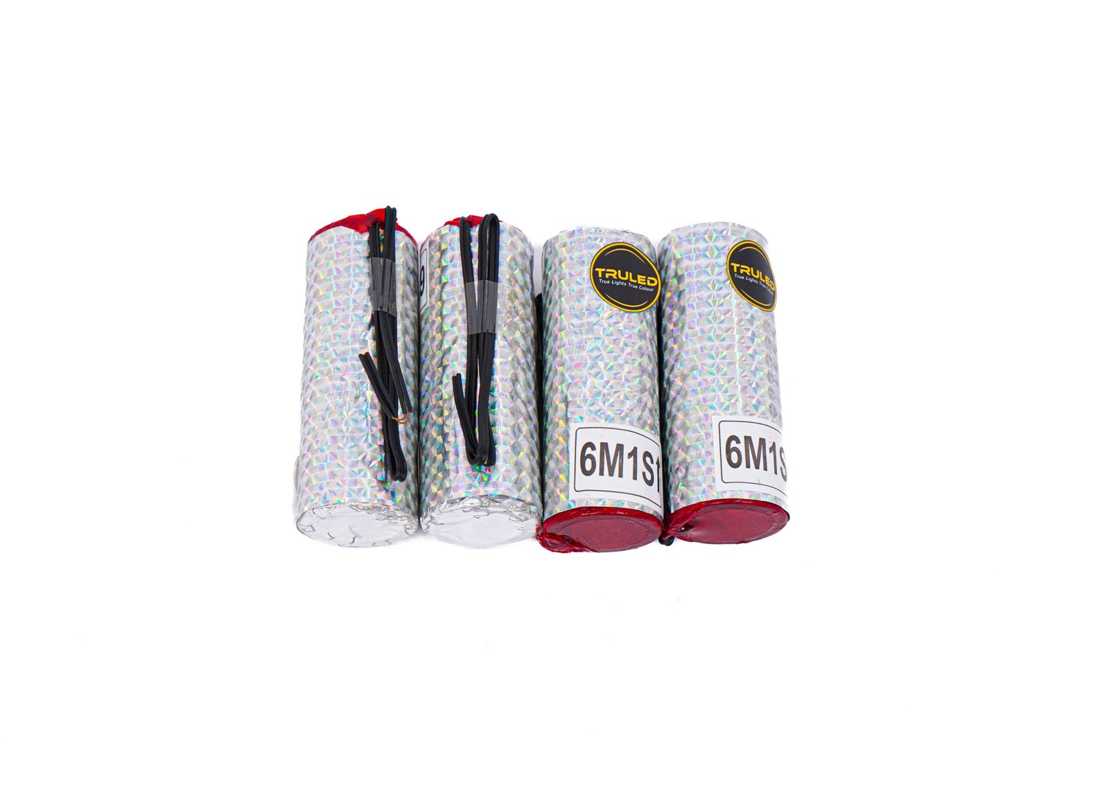 Four silver holographic cylindrical packages with red ends, wrapped in metallic foil and tied with black cords, labeled 6M1S in white stickers, arranged in a row on a white background.